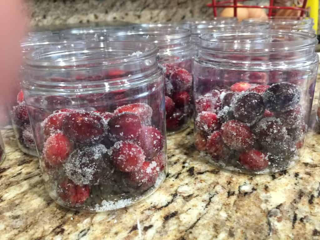 jars of sugared cranberries sitting on a granite countertop