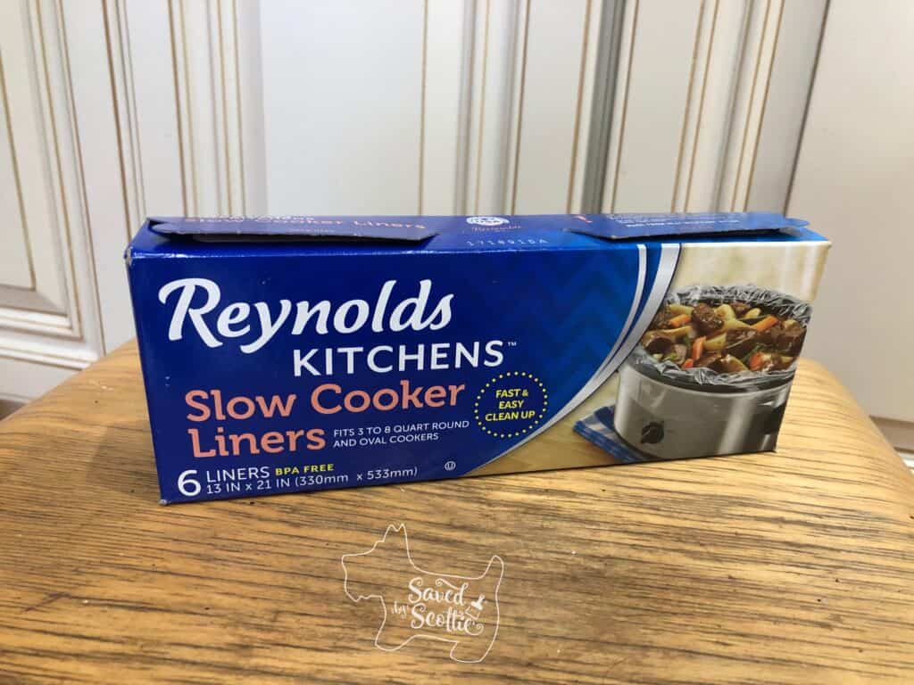 box of Reynolds kitchens slow cooker liners on a wooden stool in front of kitchen cabinets 