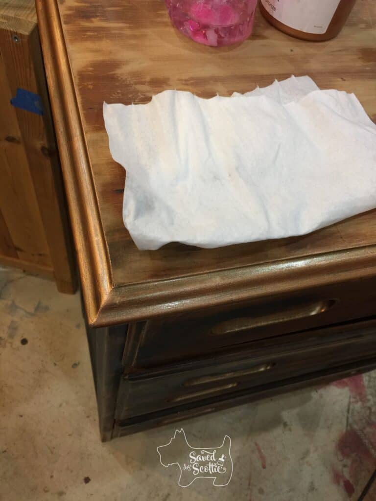 close up of top of dresser with copper  edge and white cloth placed on top 