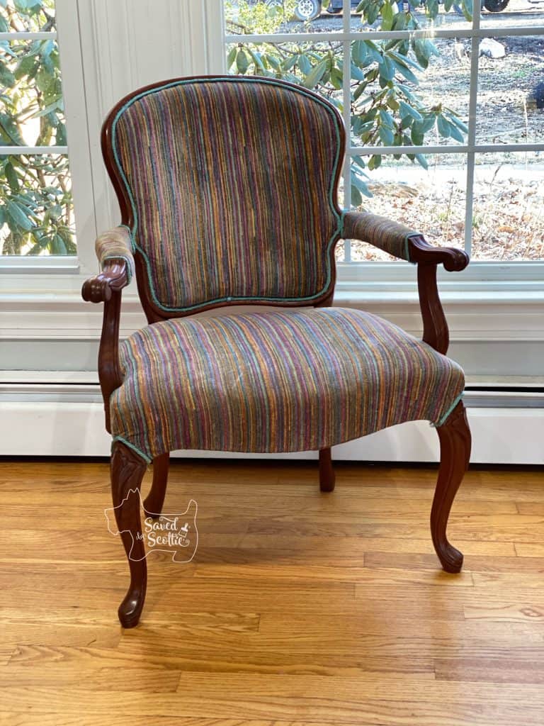finished reupholster a chair from post. Striped fabric wood framed armchair sitting in front of a window on wood floor with baseboard heaters at base of wall. 