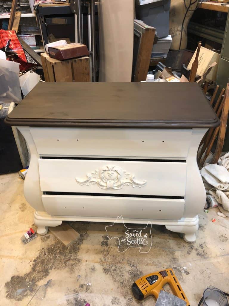 painted bombay chest in workshop environment. Body is white, top os brown with a glaze that is in the process of drying. 