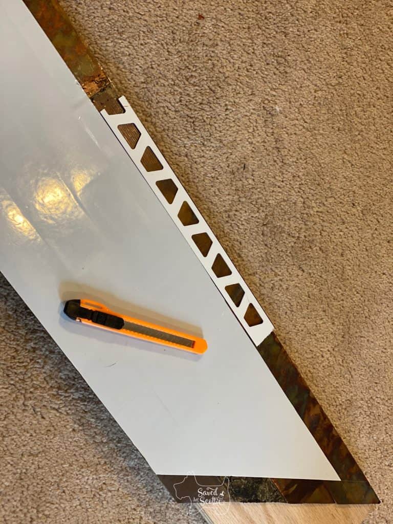 tile trim piece used to cut off self adhesive edge of metal tile and utility knife